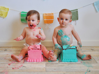 Two babies beside their birthday cakes